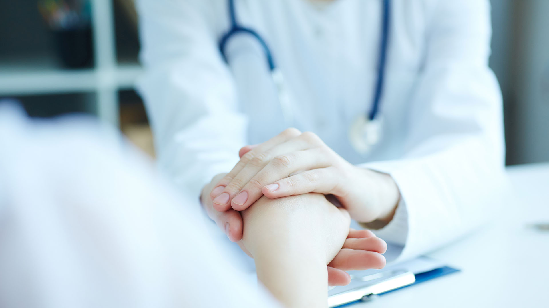 Friendly female doctor's hands holding female patient's hand for encouragement and empathy. Partnership trust and medical ethics concept.